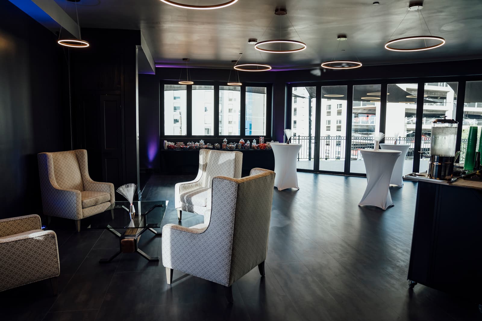 Daylit lounge with wingback chairs, candy bar, and cocktail tables