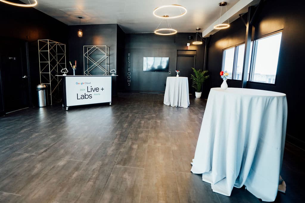 Corporate event check-in desk with branded sign and draped cocktail tables