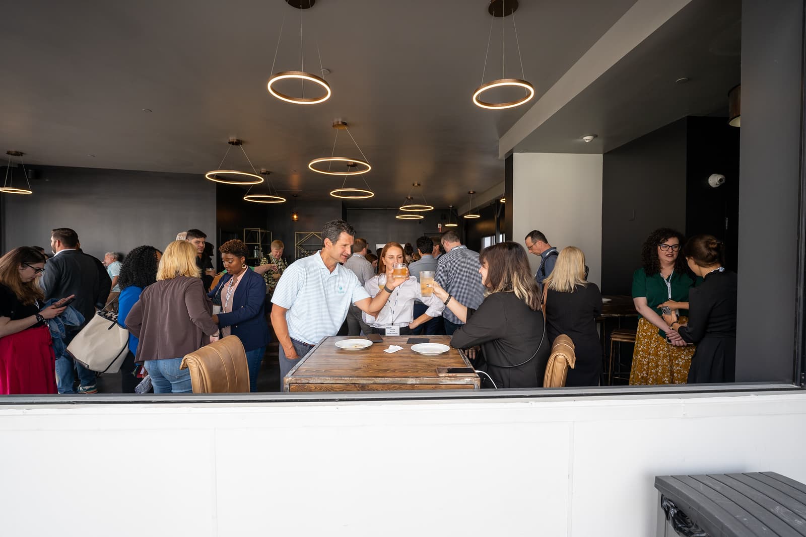 Crowded indoor happy hour seen through the terrace's open window wall