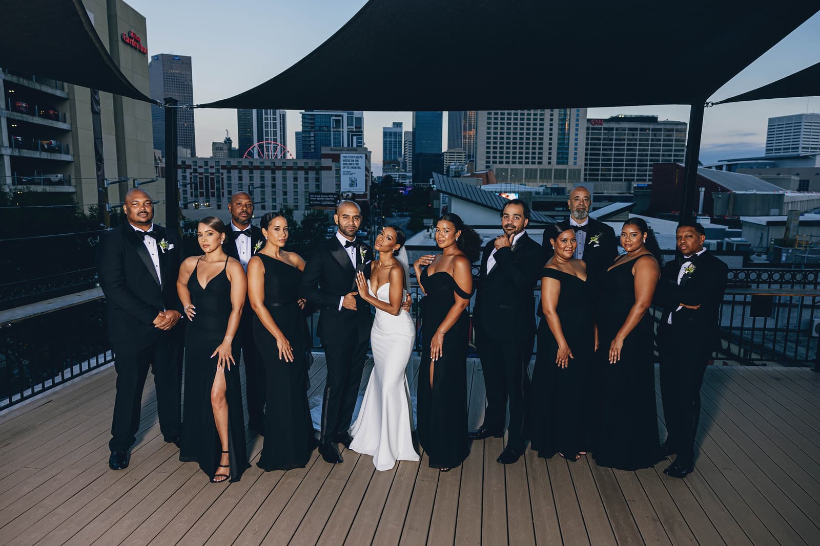 Black-tie wedding party portrait at dusk with skyline and Ferris wheel