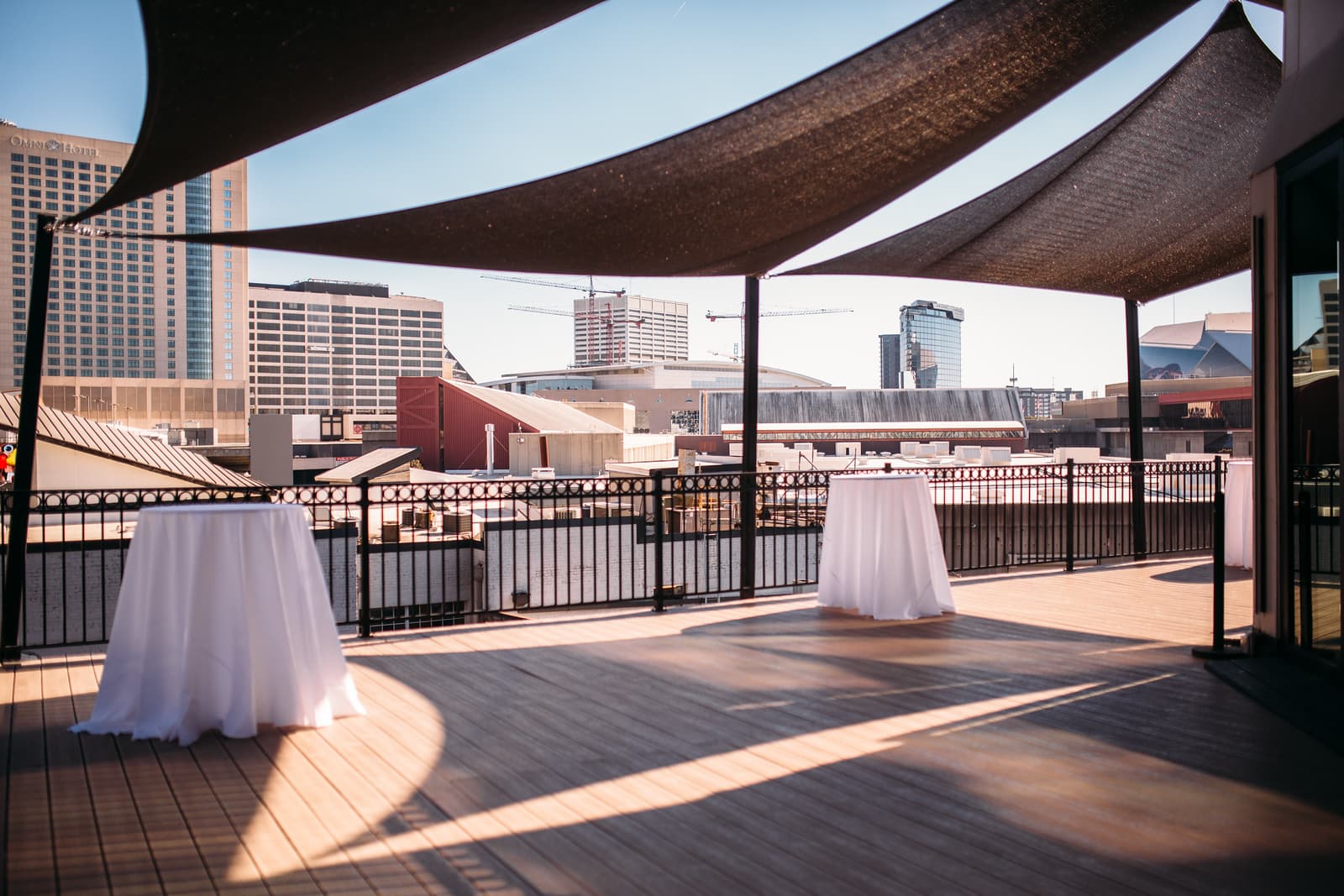 Sunny terrace under shade sails facing the Omni Hotel and downtown