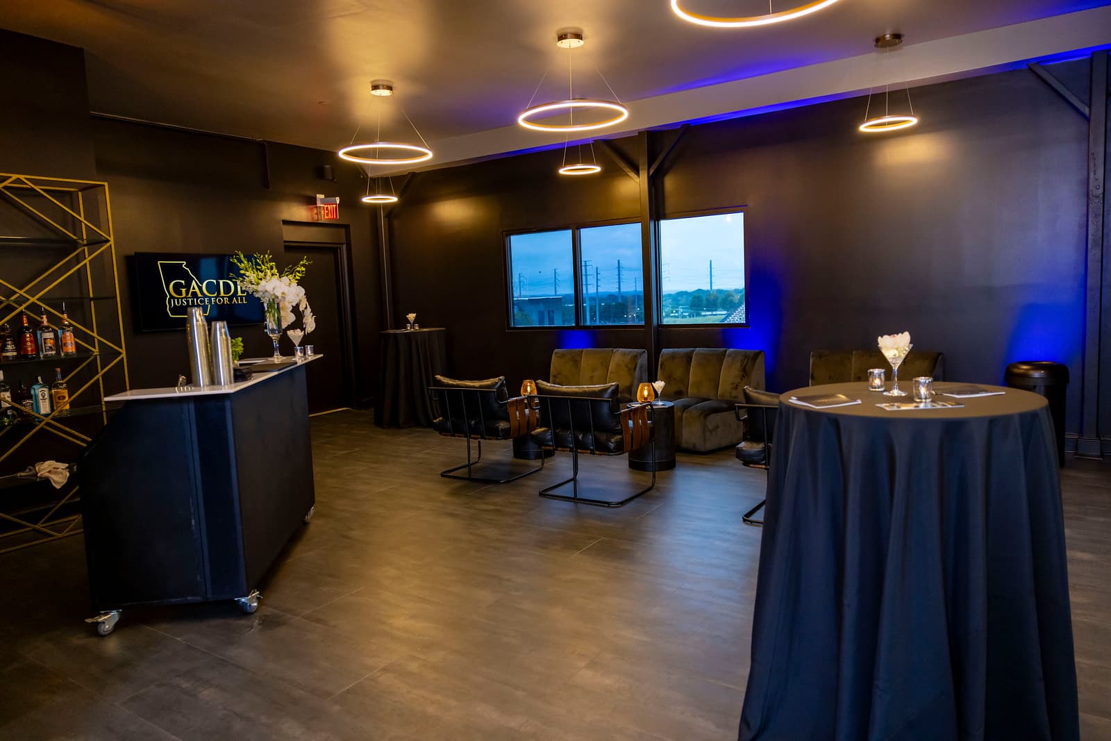 Indoor lounge at dusk with mobile bar and black cocktail tables