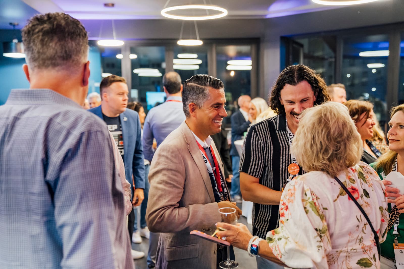Guests mingling at an indoor networking reception under ring chandeliers