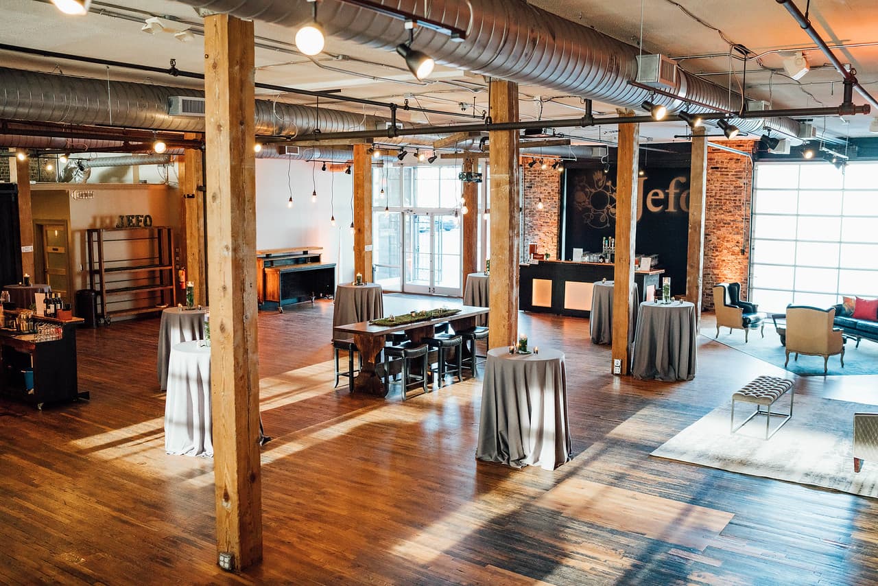 Sunlit loft with gray cocktail tables, lounge seating, and branded backdrop