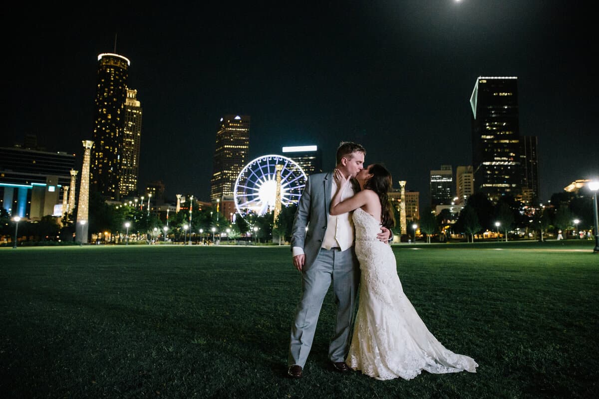 Married couple kissing with the SkyView Ferris Wheel in the background